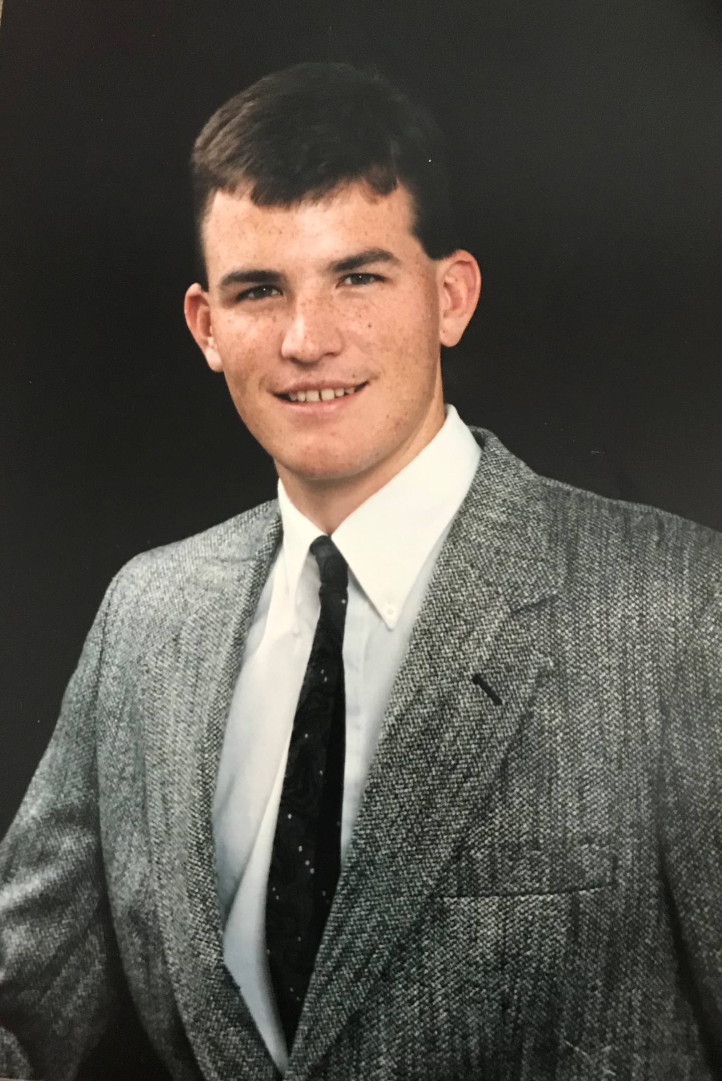 A photo of Jason Fulton smiling in a suit