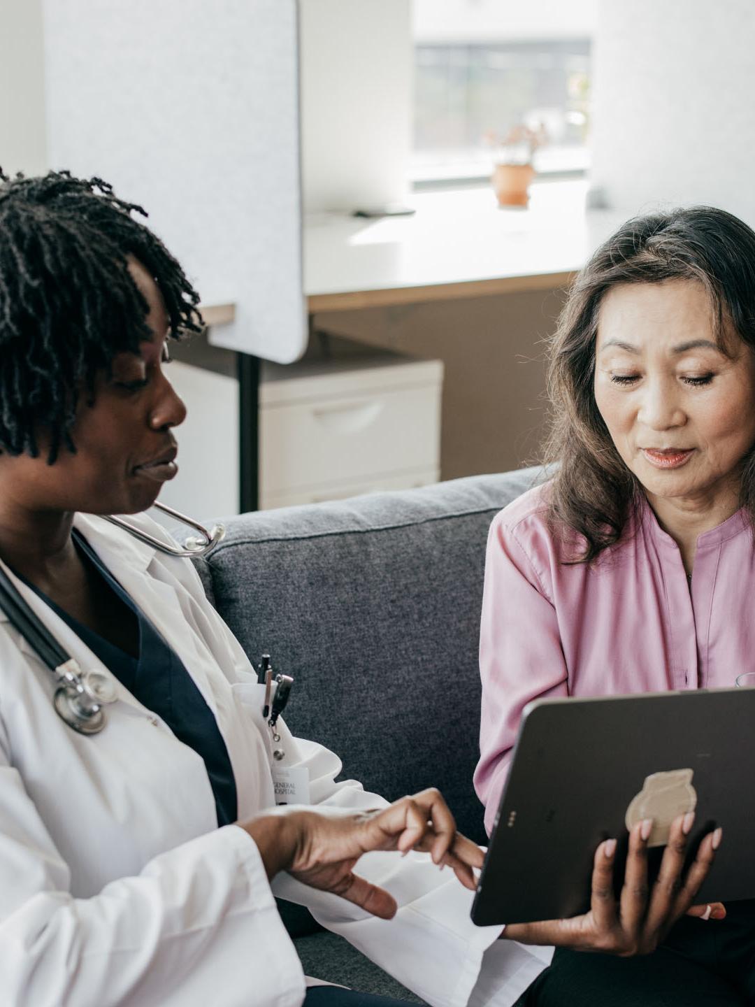 A doctor sitting with her patient reviewing medical material