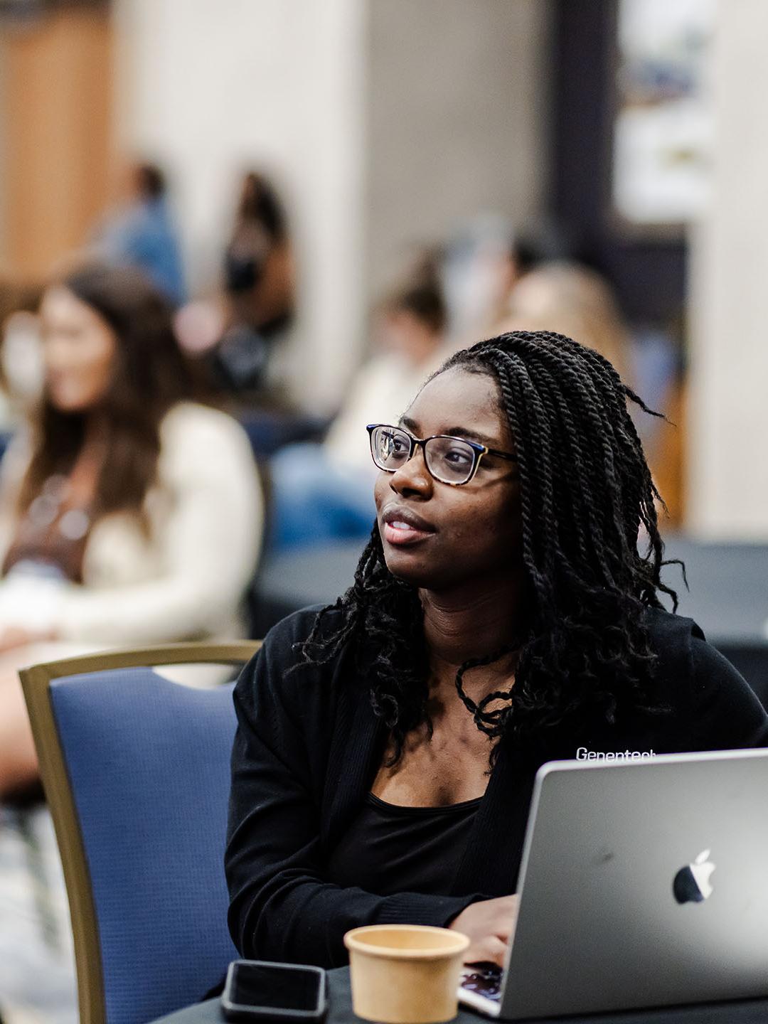 BDC 2025 - A woman on a laptop listening to a session with other people in the background