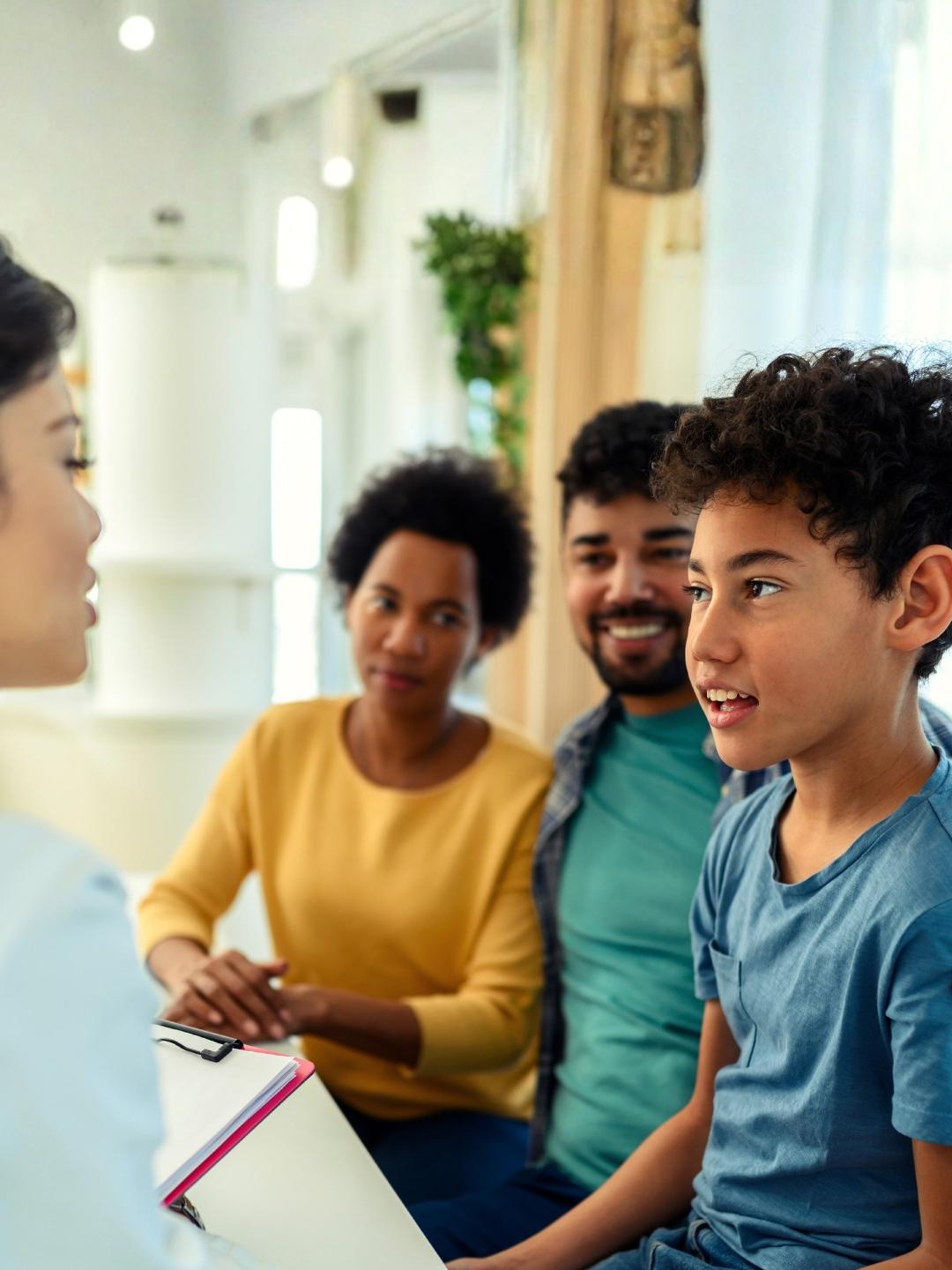 A doctor is speaking to a boy around 10 years old while his parents look on.