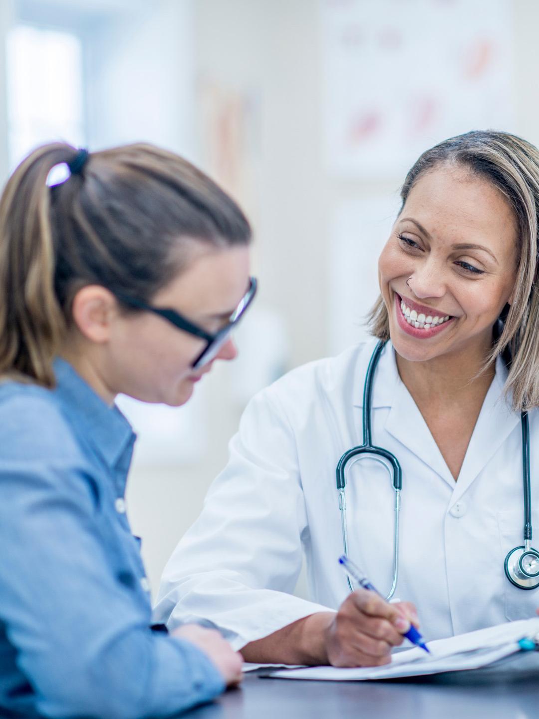 A doctor sitting across from a woman reviewing documents and charts
