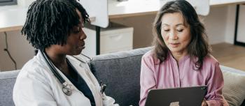 A doctor sitting with her patient reviewing medical material
