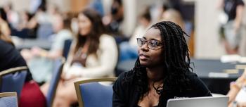 BDC 2025 - A woman on a laptop listening to a session with other people in the background