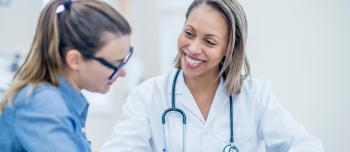 A doctor sitting across from a woman reviewing documents and charts