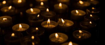 A field of small votive candles against a black background