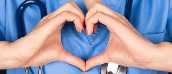 MEdical professional in blue scrubs using heart hands