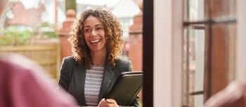Social Worker smiling at the front door of a house