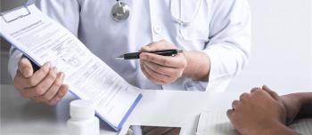 A doctor's hands pointing to a medical chart on a clipboard, holding a pen.