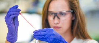 Female scientist conducting research in lab with goggles and gloves