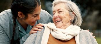 Elderly woman smiling at young woman caretaker