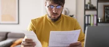 A young man on his computer reviewing bills and receipts