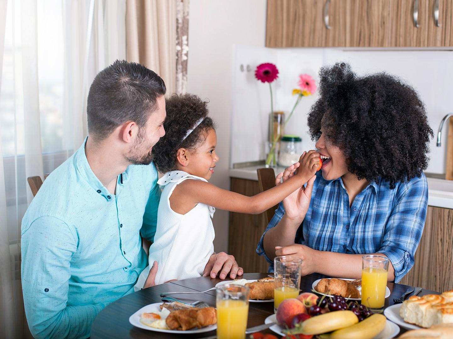 A father holding his daughter as she plays with her mother
