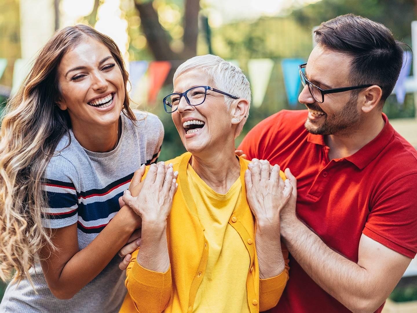 Two women and a man smiling and laughing